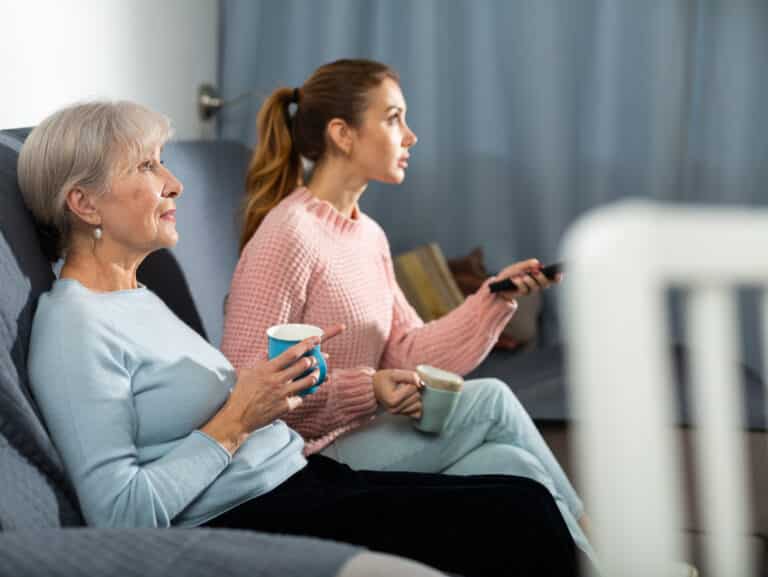 Senior and younger women watching TV